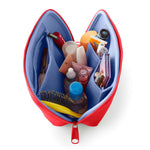 An open red neoprene cosmetics bag with light blue mesh pockets displaying assorted beauty products including a yellow hairbrush, a KUSSHI brush case, and a Banana Boat sunscreen tube