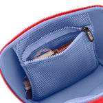 A Kusshi makeup bag interior featuring a bright red zipper, a periwinkle blue lining, a mesh zippered pocket with a KUSSHI pull, and a small brush and compact inside