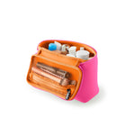 Photograph of a KUSSHI bright pink travel makeup bag open to reveal its orange mesh interior filled with various cosmetic products on a clean white background