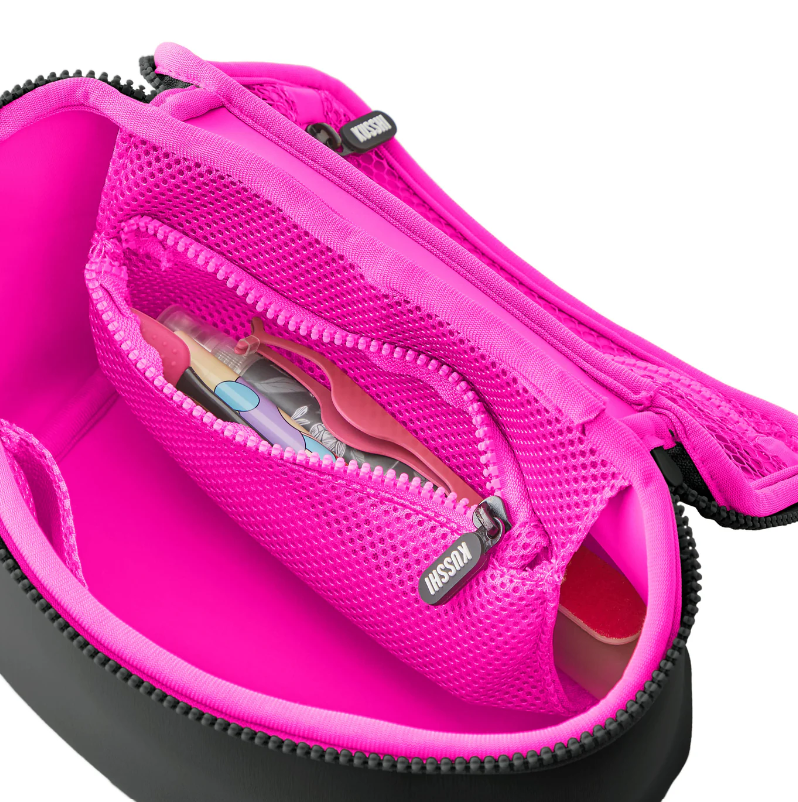 KUSSHI travel bag with a black exterior and vibrant fuchsia interior, featuring an open mesh pocket containing a small spray bottle and pink flossing tools