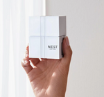 White Nest New York device with black branding and subtle vertical lines held in a hand against a bright softly lit background
