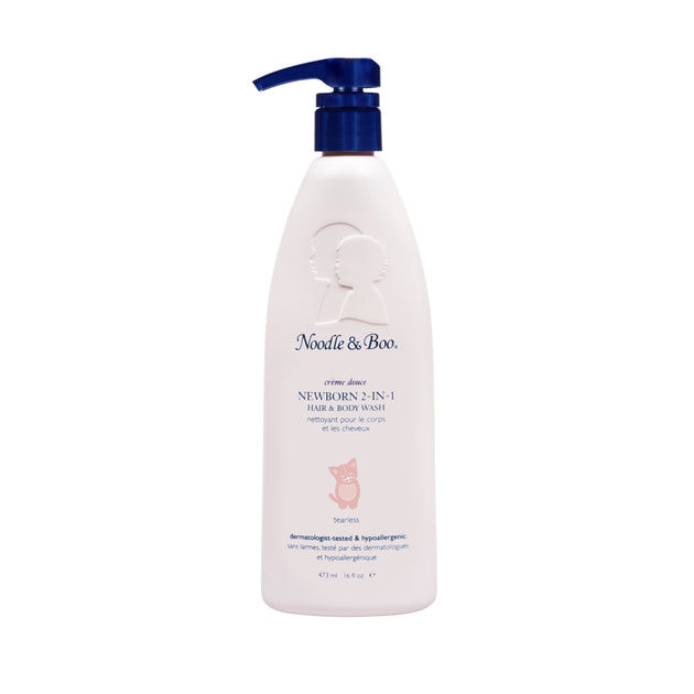 Product photography of a Noodle & Boo Newborn 2-in-1 Hair & Body Wash bottle isolated on a white background featuring a dark blue pump top, embossed baby silhouettes, and a pink kitten illustration with "Tearless" text