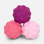Three textured sensory balls in shades of purple and pink stacked in a pyramid