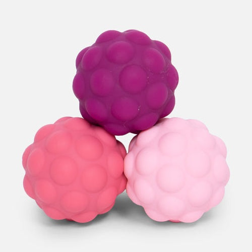 Three textured sensory balls in shades of purple and pink stacked in a pyramid