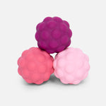 Three textured sensory balls in shades of pink and purple stacked in a pyramid