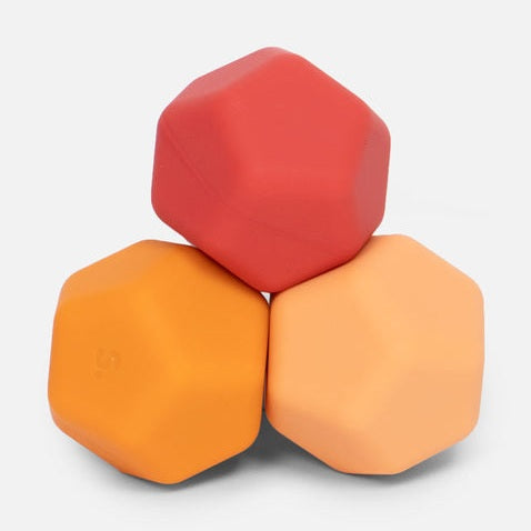 Three stacked hexagonal silicone sensory blocks in red orange and light orange