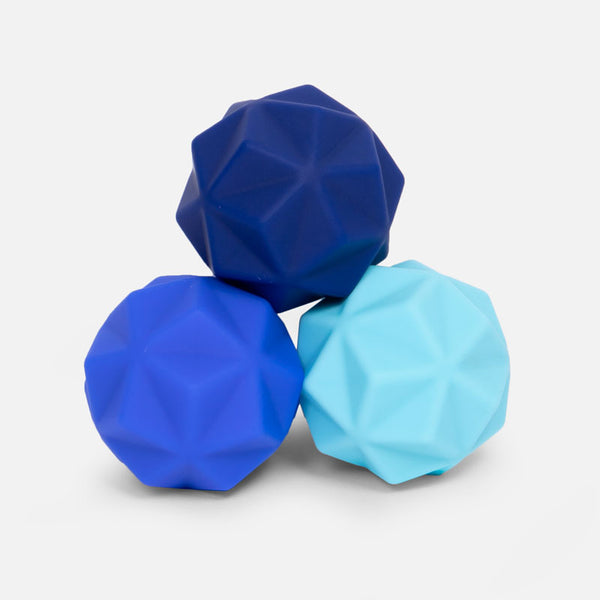 Three geometric textured balls in shades of blue stacked on a white background