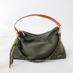 Product photograph of an olive green nylon hobo bag on a white studio background featuring a tan leather handle, a thick green and beige knotted rope strap, and three small gold studs at the corner