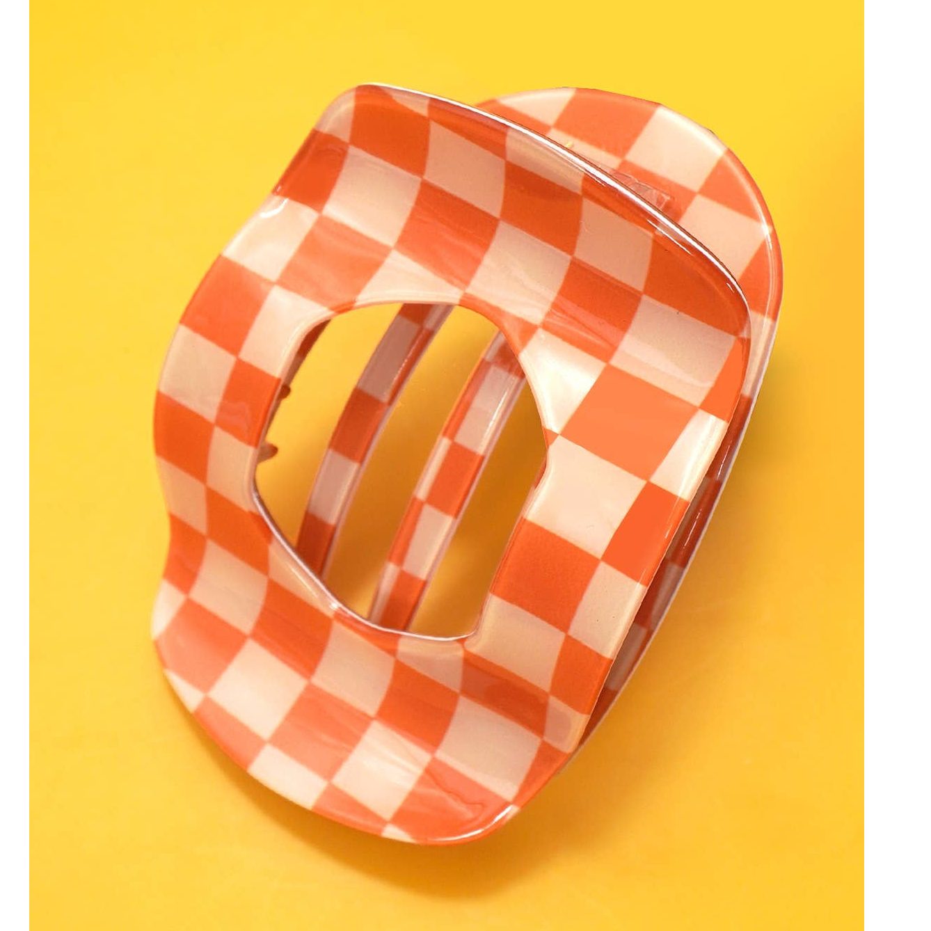 Orange and white checkered hair claw clip on a yellow background