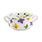 White ceramic soup bowl with two handles decorated with vibrant purple, gold, and green Mardi Gras fleur-de-lis motifs and matching speckled paint inside the rim
