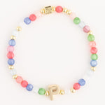 Jewelry multicolor beaded bracelet featuring gold accent beads a central gold initial P charm and a square gold bead with an embossed design
