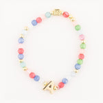 Beaded bracelet featuring translucent pink blue green red and clear glass beads gold spacer beads a prominent gold initial A charm and a square patterned gold clasp
