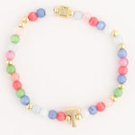 Multicolor pastel glass beaded bracelet with alternating gold spacer beads, a gold T-shaped charm, and a decorative gold rectangular clasp