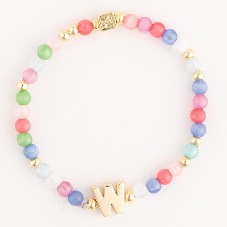 A colorful beaded bracelet featuring an array of pastel pink, green, blue, and white beads, interspersed with small gold accent beads, a prominent gold letter W, and a square gold clasp with a star-like etched design