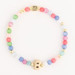 Beaded bracelet featuring a gold initial B charm, small gold spherical beads, a square gold bead with an etched design, and pastel colored beads in shades of pink, green, blue, white, and coral