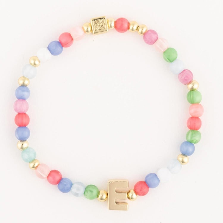 Beaded bracelet featuring an assortment of pastel pink blue green and white beads with small gold spacer beads a prominent gold initial E charm and a gold square clasp engraved with a cross-like design