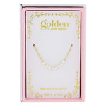 Product photo by Golden by Jane Marie of an 18K gold plated necklace with a row of white pearls, displayed in a pink and white box featuring gold scrollwork and '18K GOLD PLATED' text
