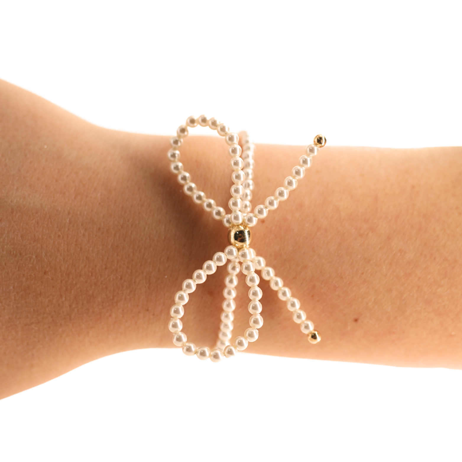 Photograph of a delicate pearl bow bracelet featuring a central gold bead and small gold tips on a person's wrist against a stark black background