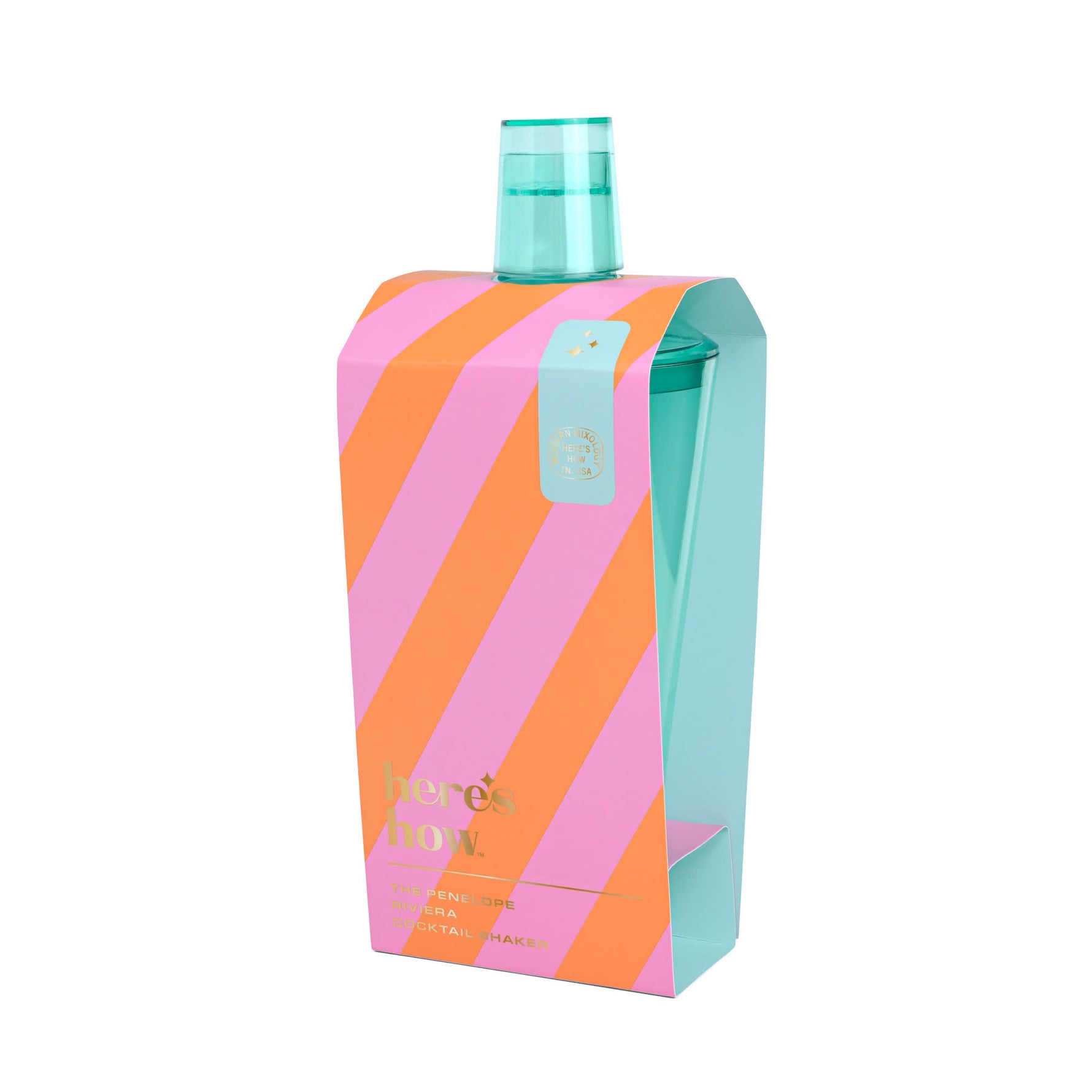 Product photography of a here's how Penelope Riviera cocktail shaker set, showcasing a teal blue shaker in packaging with bold pink and orange diagonal stripes and gold details including a small star emblem