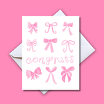 Printed greeting card featuring nine unique hand-drawn pink bow illustrations and the word Congrats in a playful pink script on a white card against a vibrant pink background with a white envelope