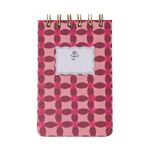 A small spiral-bound notebook with a pink and dark pink geometric quatrefoil pattern cover, a white scalloped label featuring a black floral icon, and gold coil binding