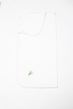 White baby blanket on a plain background with a delicate pink scalloped edge and a small embroidered bouquet of pink tulips tied with a yellow ribbon