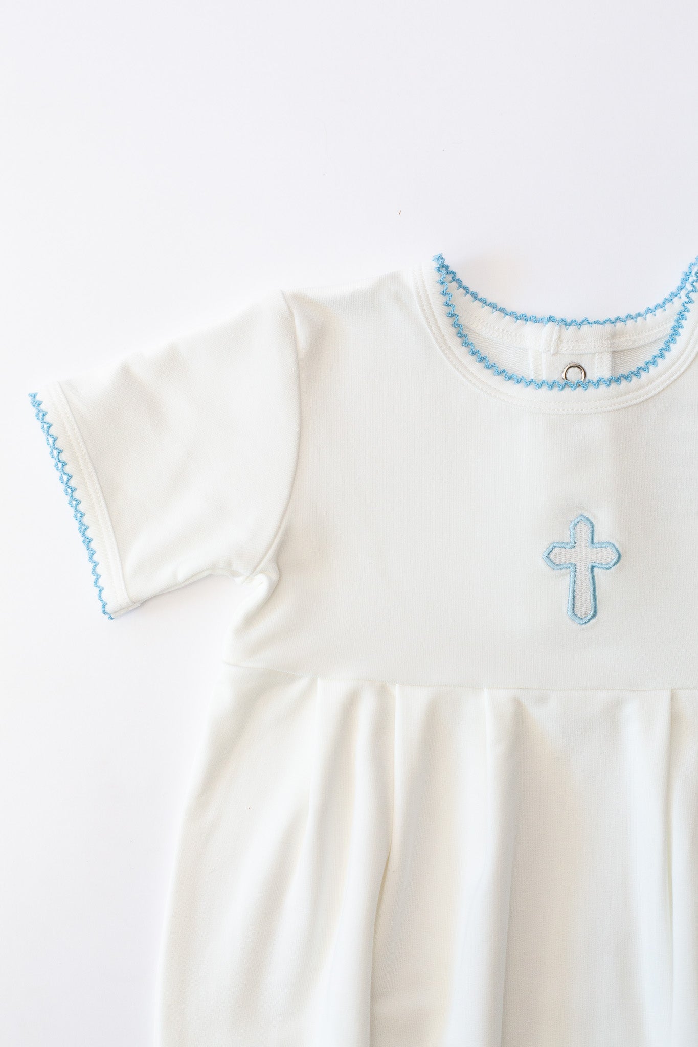 White baby Christening outfit featuring a light blue embroidered cross on the chest and matching light blue picot trim around the neckline and short sleeves