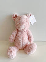 Plush toy by Mudpie, a fuzzy pastel pink Rosy the Pig stuffed animal sitting upright against a plain light background with a white tag showing 'Rosy the Pig' and stars