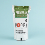 Product photograph of a white stand-up pouch of Poppy Hand-Crafted Popcorn Parmesan & Black Pepper flavor, made in Asheville NC, featuring a red poppy logo and a dark green top band with scattered white dots