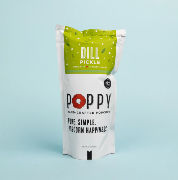 Poppy Hand-Crafted Dill Pickle popcorn in a white pouch with a lime green top section featuring a red poppy logo and "Made with love in Asheville NC" text against a light blue background