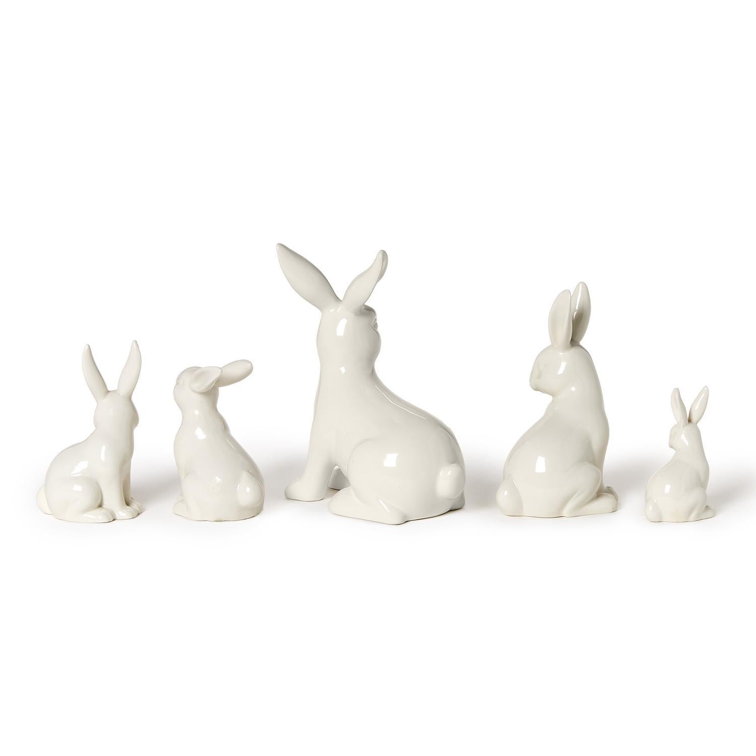 Ceramic collection of five glossy white rabbit figurines of various sizes arranged against a plain white background