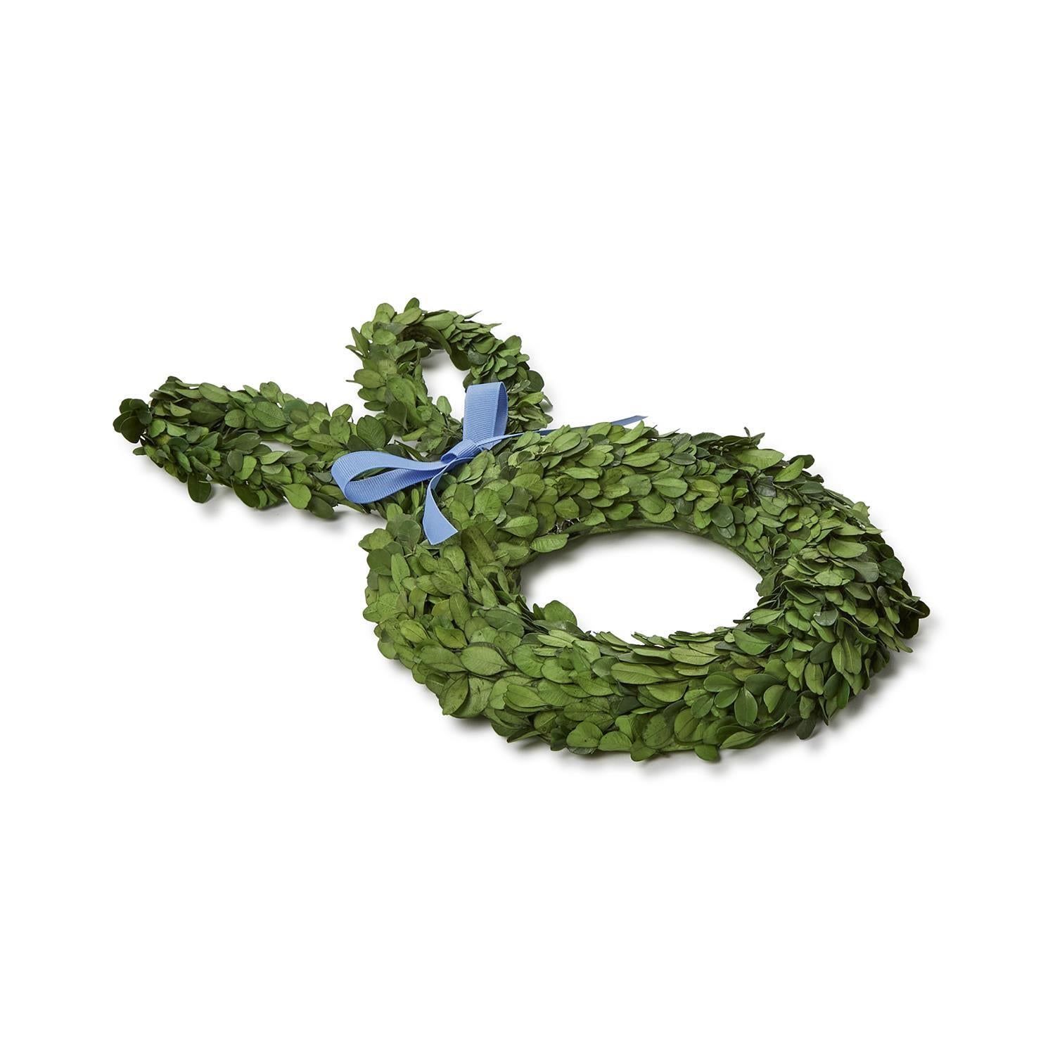 Preserved boxwood bunny-shaped wreath made of vivid green leaves and adorned with a delicate light blue ribbon tied at its neck on a clean white background