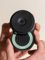 Hand holding a black car fragrance diffuser with a mint ring
