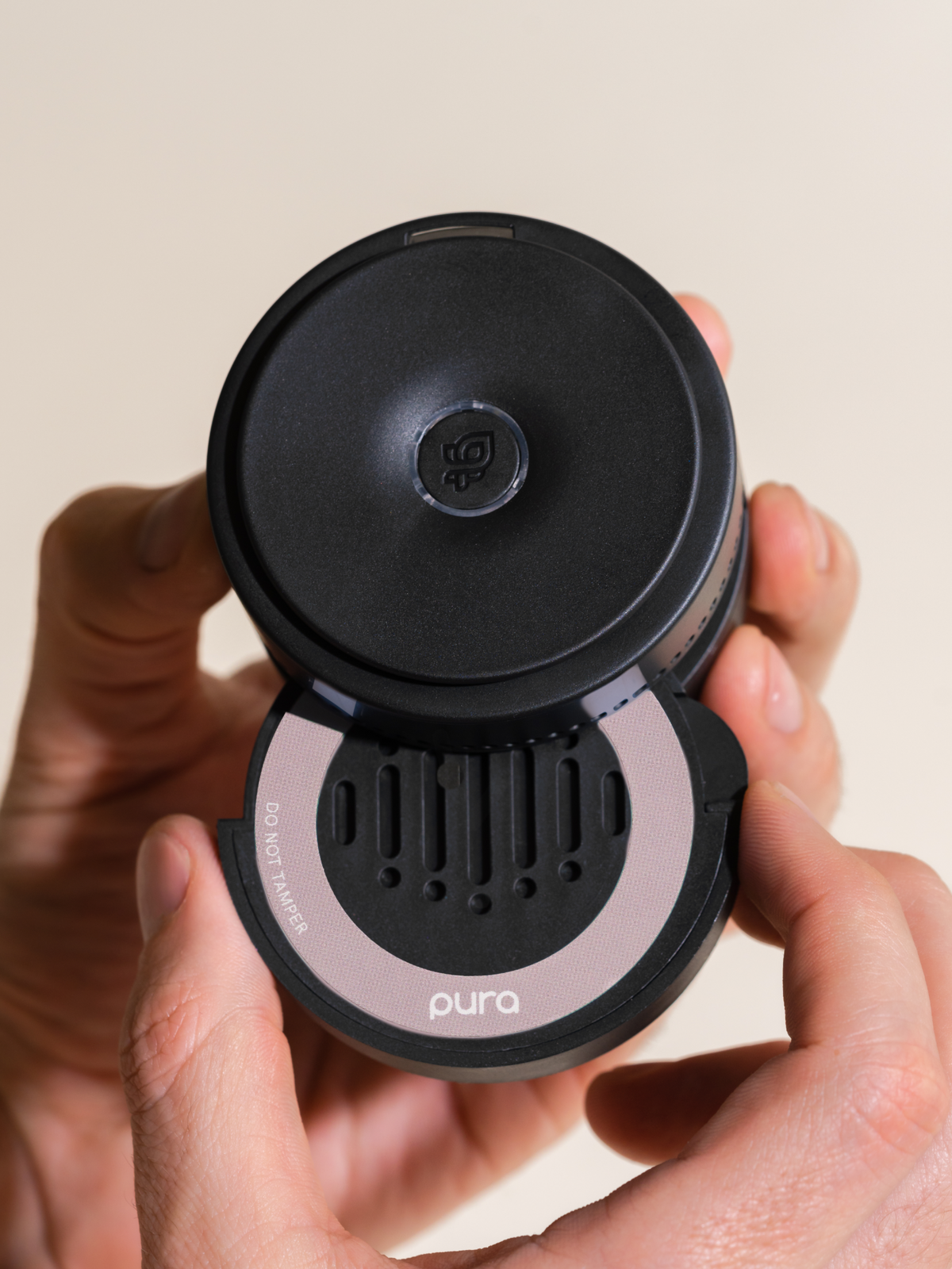 Hand holding a black car fragrance diffuser with a pink ring