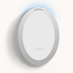A white oval Pura smart fragrance diffuser with the pura logo and a subtle blue light from its top slot casting a soft shadow on a light background