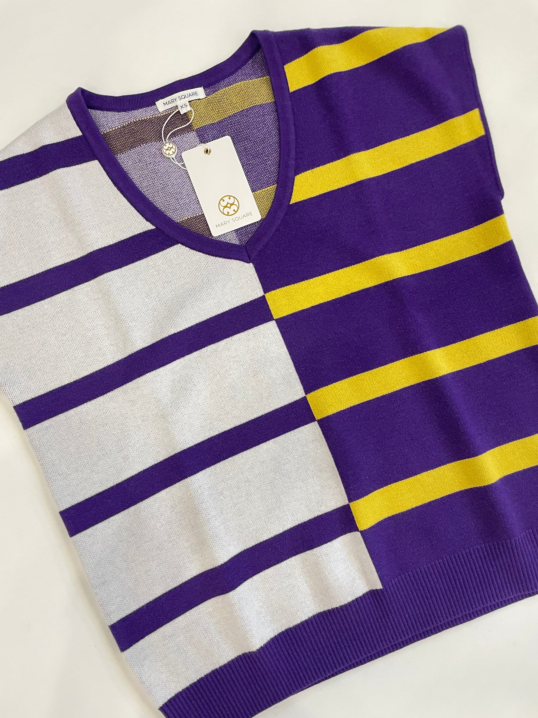 Mary Square knitwear V-neck top featuring a unique color-blocked design with wide horizontal stripes, combining white and purple on the left and vibrant purple and yellow on the right, with the brand tag visible
