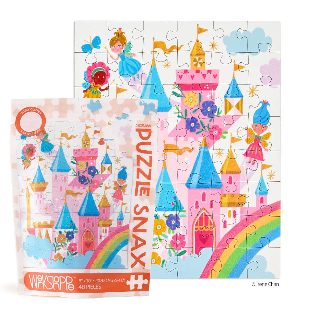 Jigsaw puzzle illustration by Irene Chan depicting a whimsical pink castle in a fairytale kingdom featuring a vibrant rainbow, flying fairies, and colorful floral accents