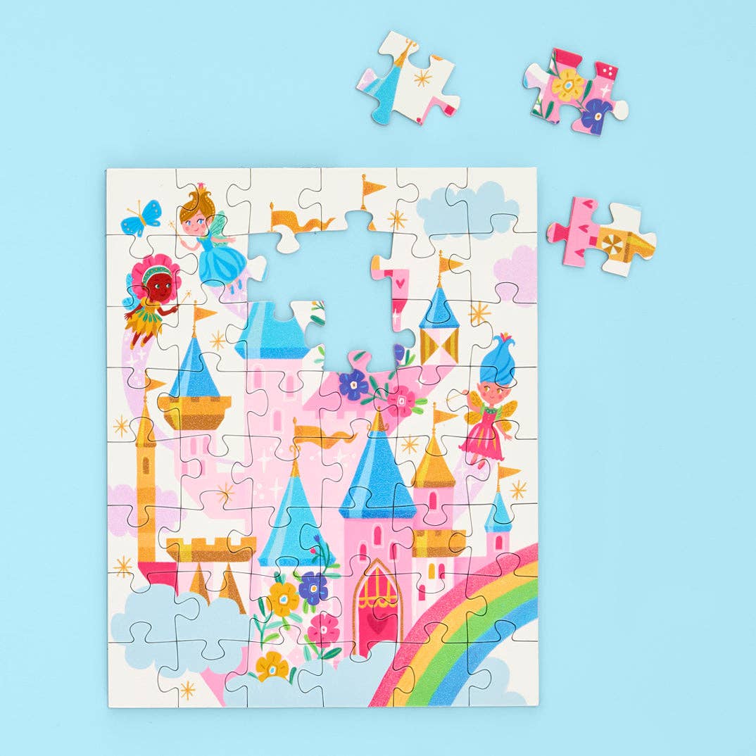 Whimsical illustration jigsaw puzzle of a magical fairy kingdom featuring a pink and blue turreted castle, flying fairies with colorful wings, and a vibrant rainbow arching across the foreground