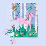 Illustrated children's puzzle featuring a pink unicorn with rainbow mane and tail in a whimsical forest clearing defined by white birch trees, an owl, a white rabbit, and vibrant wildflowers