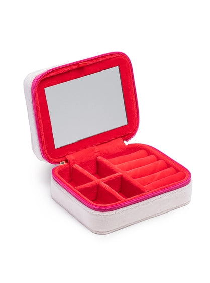 Photograph of an open compact travel jewelry box with a light grey exterior, hot pink zipper, and a vibrant pink interior featuring a mirror, ring rolls, and four square compartments for organization