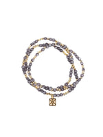 Jewelry: a double-strand beaded bracelet with gray variegated beads, small gold spherical spacers, and a square gold charm featuring an interwoven knot pattern, presented against a white background