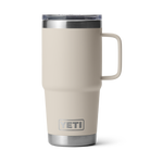 YETI Rambler product photograph featuring a tall light beige travel mug with a robust integrated handle, clear MagSlider lid, polished stainless steel accents, and the iconic YETI logo, all isolated on a black background
