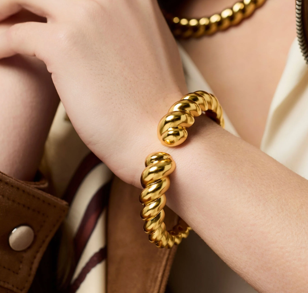 Gold twisted cuff bracelet worn on a wrist
