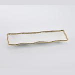 White ceramic rectangular serving platter with a subtly wavy edge adorned by a continuous delicate gold beaded border