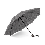 Open umbrella with black canopy covered in small white polka dots on a white background showcasing a dark handle with wrist strap