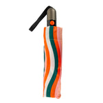 A studio photo of a compact automatic umbrella folded, displaying a lively striped pattern in white, orange, dark teal, and light pink, with a metallic grey handle, bright orange open-close button, and black wrist strap