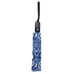 Folded umbrella showcasing a vibrant blue and white tie-dye spiral pattern, featuring a black handle and a bright blue push button