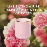 Pink candle in a glass jar with gold rim against a background of pink roses