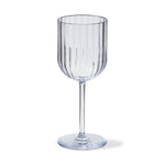 Clear stemmed glass featuring distinctive vertical fluting on its bowl casting a soft shadow