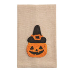 Yarn appliqué artwork featuring a smiling orange jack-o'-lantern pumpkin with black facial features wearing a black witch's hat adorned with an orange buckle, all crafted with textured rope-like yarn on a neutral beige linen fabric